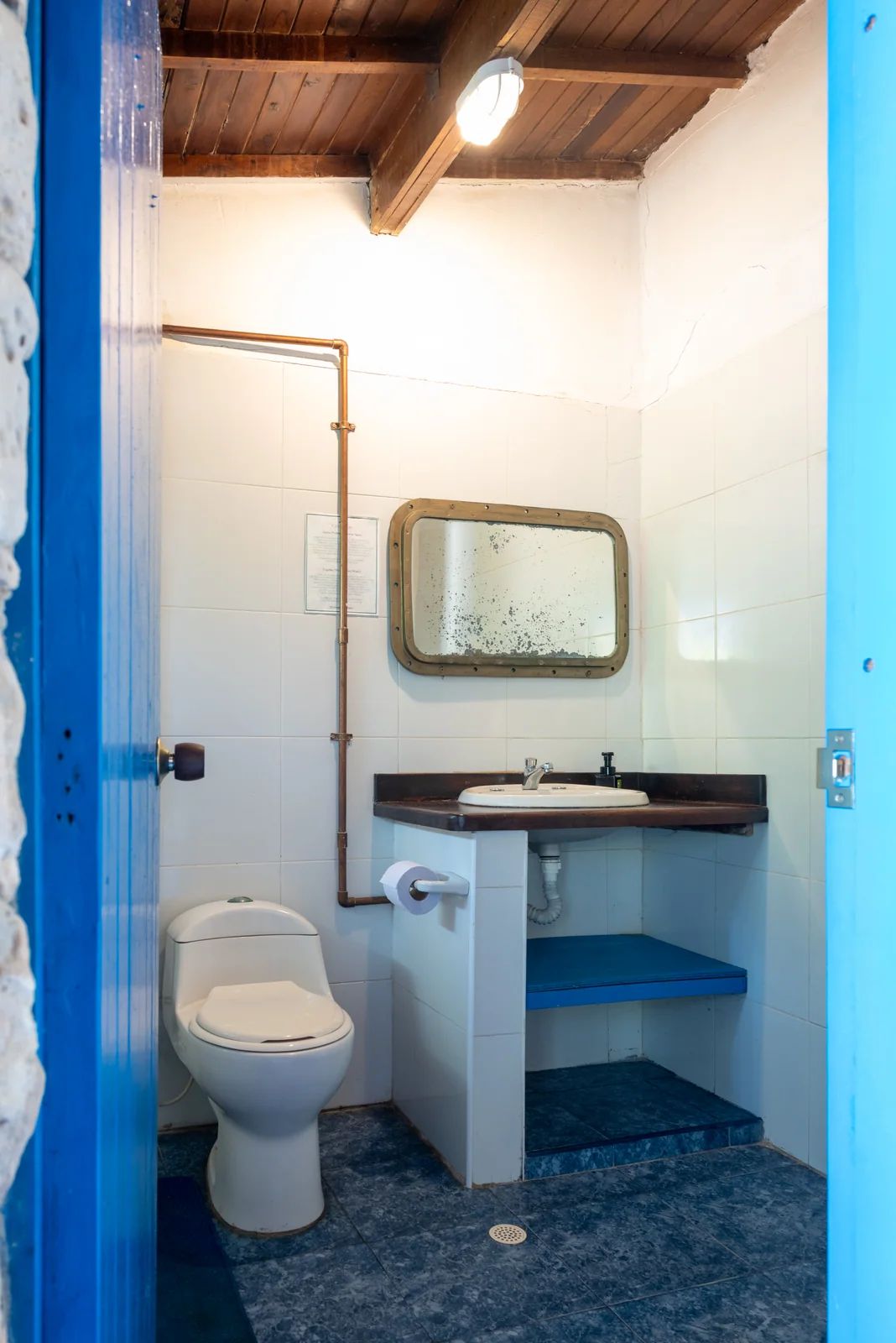Baño sur con espejo y puerta azul