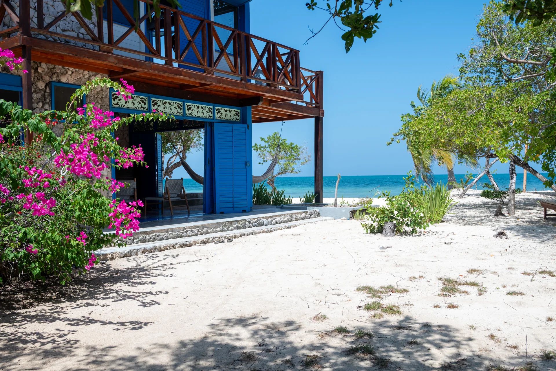 Puertas azules, balcón y acceso de arena