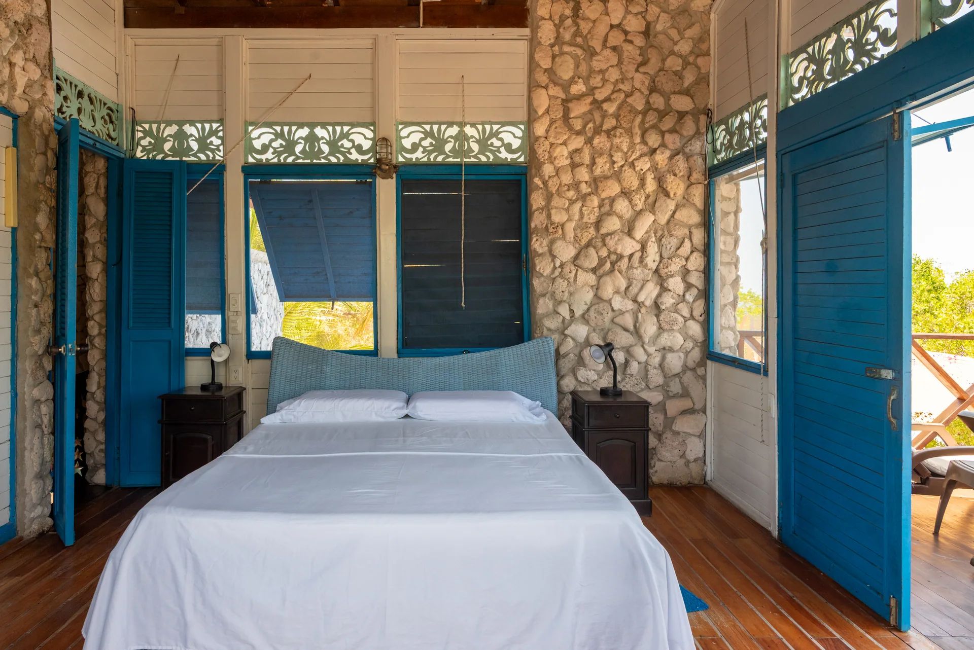 Upstairs master bedroom at Casa Gaviota villa rental with double bed, blue shutters, and sea view
